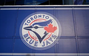 Toronto Blue Jays team logo featuring a blue jay head and red maple leaf displayed on a blue stadium wall.